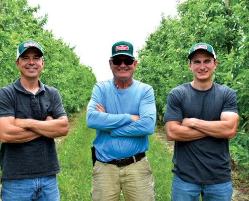 Michael, Jim, and Brandt Swindeman standing in SweeTango Orchard at Applewood Orchards Inc.