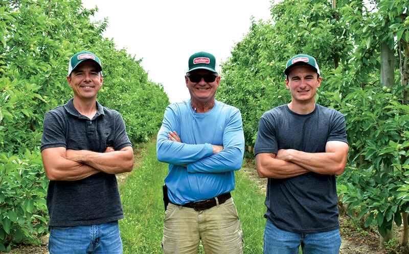 Michael, Jim, and Brandt Swindeman standing in SweeTango Orchard at Applewood Orchards Inc.
